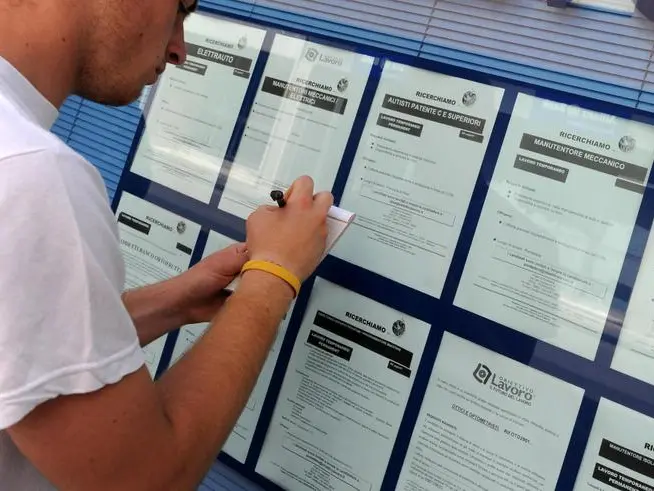 Un ragazzo davanti a un'agenzia interinale (Franco Silvi, Ansa)