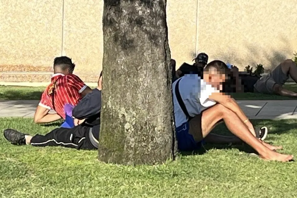 Migranti attendono al porto di Olbia di essere imbarcati su una nave per la Penisola