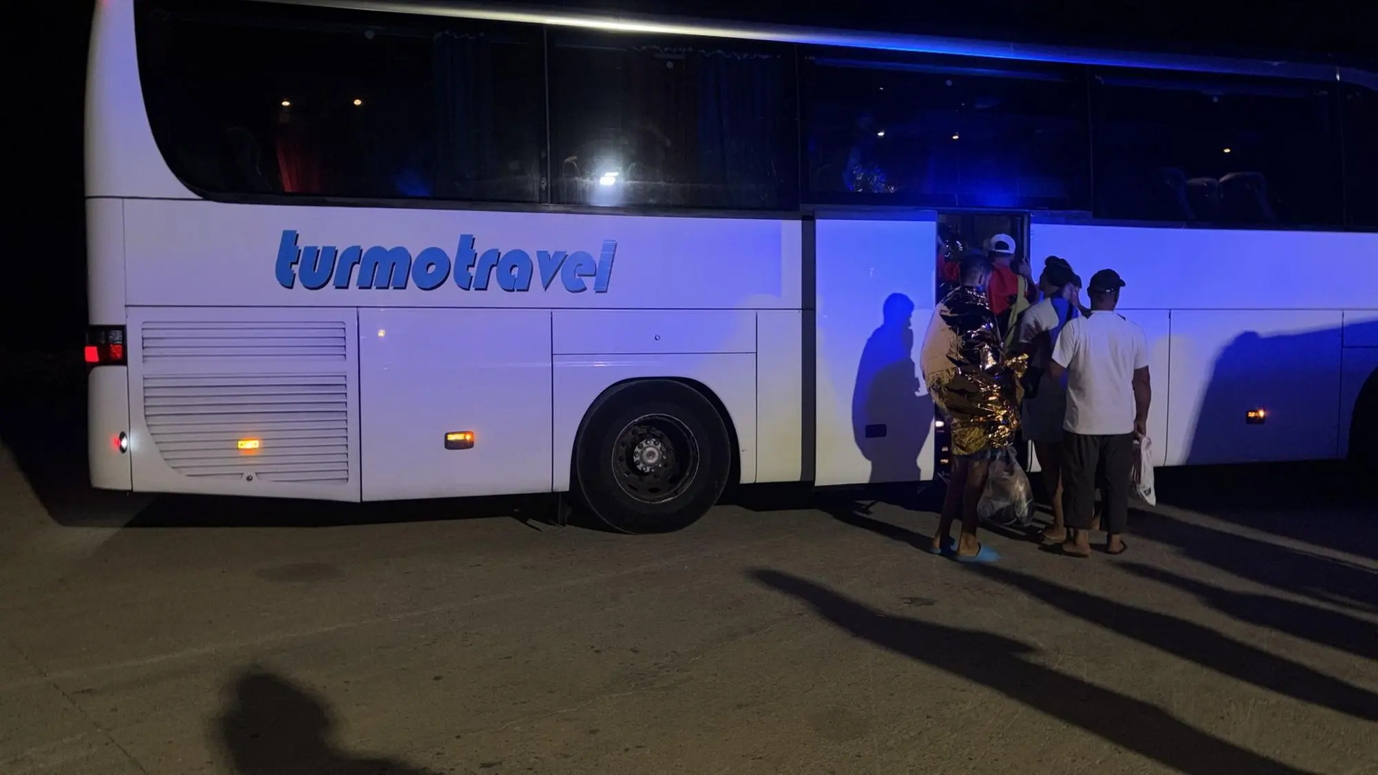 I migranti salgono su un autobus dopo lo sbarco a Cala Verde