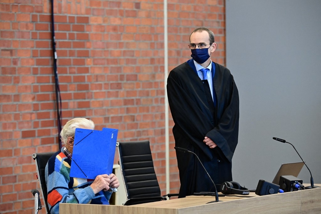 Defendant Josef S (L) sits next to his lawyer Stefan Waterkamp and hides his face behind a folder as he waits for the start of his trial in Brandenburg an der Havel, northeastern Germany, on October 7, 2021. - The 100-year-old former concentration camp guard will become the oldest person yet to be tried for Nazi-era crimes in Germany when he goes before court charged with complicity in mass murder. The suspect, identified as Josef S., stands accused of "knowingly and willingly" assisting in the murder of 3,518 prisoners at the Sachsenhausen camp in Oranienburg, north of Berlin, between 1942 and 1945. (Photo by Tobias Schwarz / AFP)