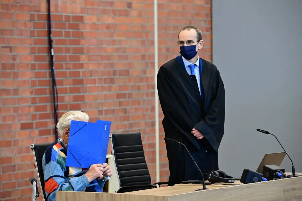 Defendant Josef S (L) sits next to his lawyer Stefan Waterkamp and hides his face behind a folder as he waits for the start of his trial in Brandenburg an der Havel, northeastern Germany, on October 7, 2021. - The 100-year-old former concentration camp guard will become the oldest person yet to be tried for Nazi-era crimes in Germany when he goes before court charged with complicity in mass murder. The suspect, identified as Josef S., stands accused of "knowingly and willingly" assisting in the murder of 3,518 prisoners at the Sachsenhausen camp in Oranienburg, north of Berlin, between 1942 and 1945. (Photo by Tobias Schwarz / AFP)