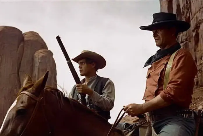 L'attore John Wayne in una scena di un film western