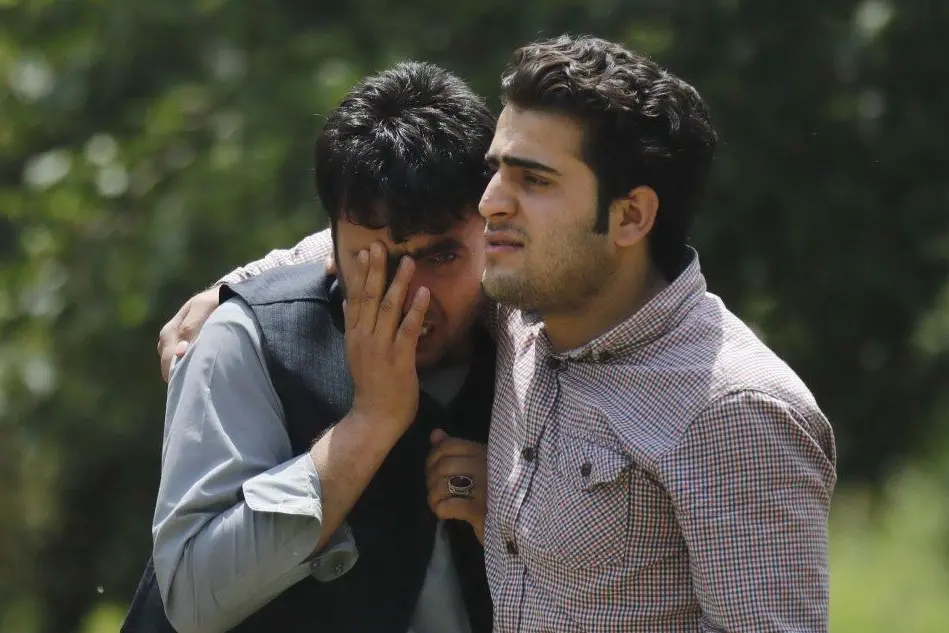 Due uomini piangono la vittima di un attentato (foto d'archivio)