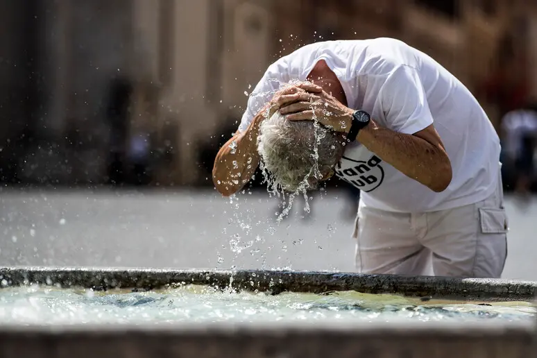 Un uomo si rinfresca con l’acqua di una fontana per difendersi dal caldo