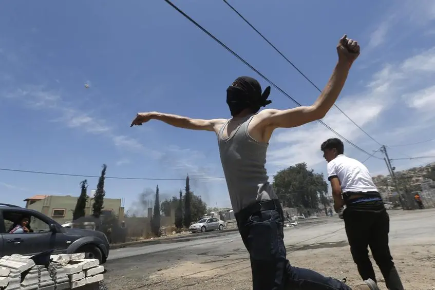 epa09254946 Palestinian protester throws stones during clashes with Israeli troops after a protest against Israeli settlements at Beta village near the West Bank City of Nablus, 08 June 2021. EPA/ALAA BADARNEH