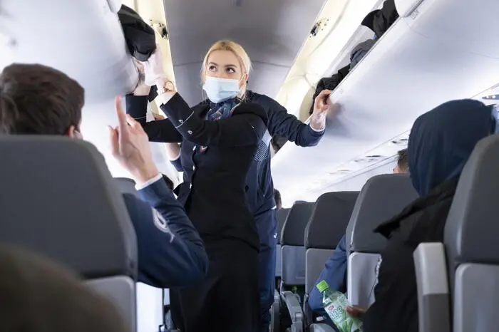 epa09099182 Flight attendant wearing a protective face mask speaks with passengers in an airplane of Bulgaria Air that boarded a flight to Sofia in Bulgaria during the coronavirus disease (COVID-19) outbreak, in Zurich, Switzerland, 26 March 2021. Switzerland as many countries in Europe impose coronavirus restrictions to fight against the spread of coronavirus COVID-19. EPA/LAURENT GILLIERON