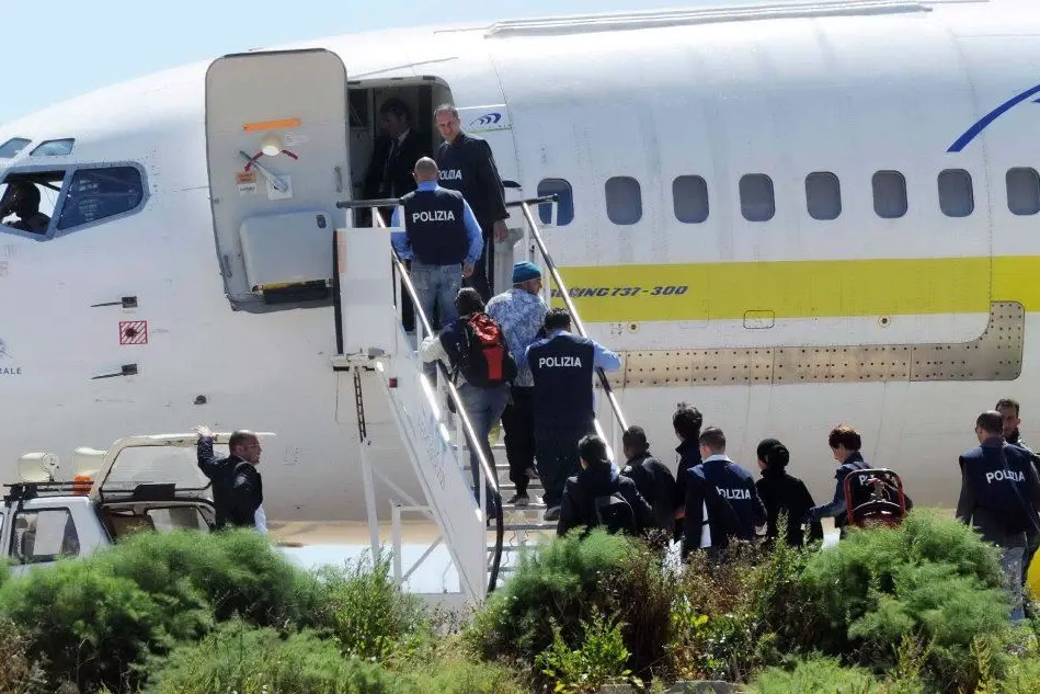 Polizia scorta dei migranti su un volo per il rimpatrio (foto Ansa)