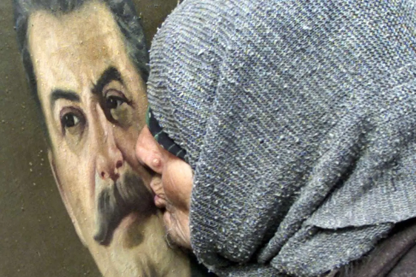 5 marzo 2004, un'anziana bacia un ritratto di Stalin durante un'iniziativa per commemorare il 51esimo anniversario della morte del dittatore a Gori, in Georgia, sua citt&agrave; natale (archivio Unione Sarda)