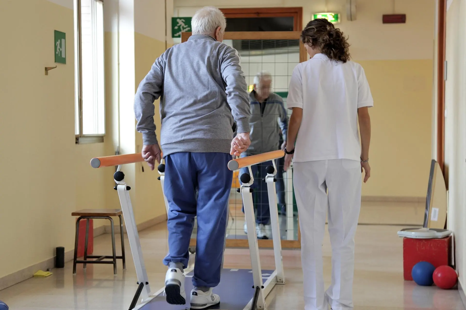 Una fisioterapista segue gli esercizi di un paziente anziano