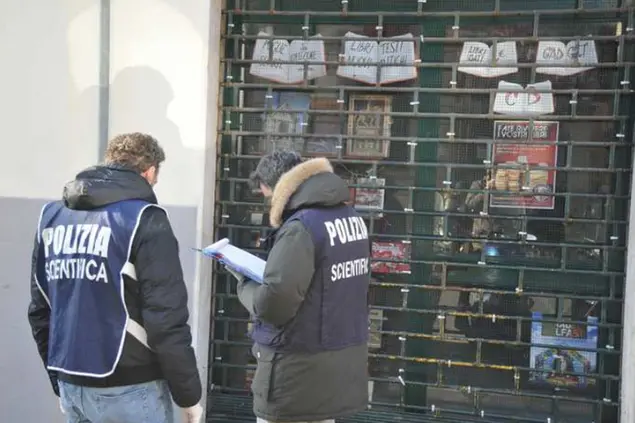 Polizia scientifica davanti alla libreria dove esplose l'ordigno (foto Ansa)