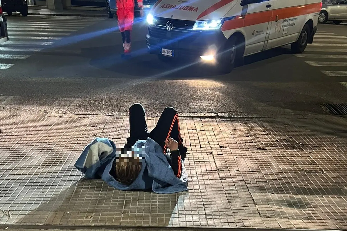 La donna sdraiata davanti all'ingresso delle ambulanze (L'Unione Sarda)