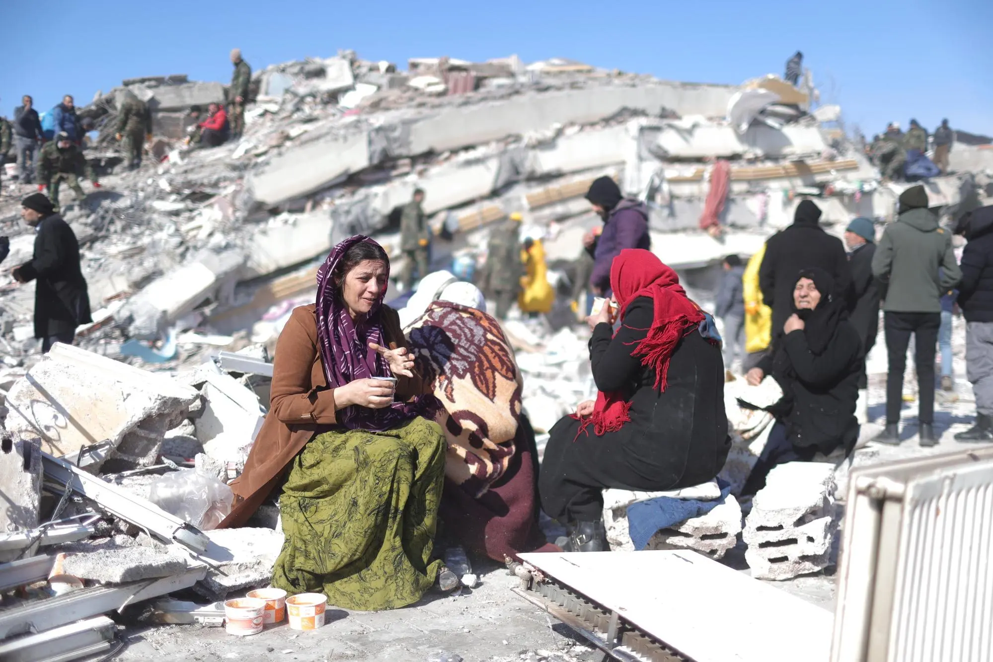 epa10454518 Women cry near a collapsed building at the city of Kahramanmaras, southeastern Turkey, 08 February 2023. More than 11,000 people have died and thousands more injured after two major earthquakes struck southern Turkey and northern Syria on 06 February. Authorities fear the death toll will keep climbing as rescuers look for survivors across the region. EPA/ABIR SULTAN