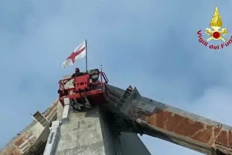 La bandiera dei Vigili del fuoco issata sui resti del ponte (Foto Vigili del fuoco)