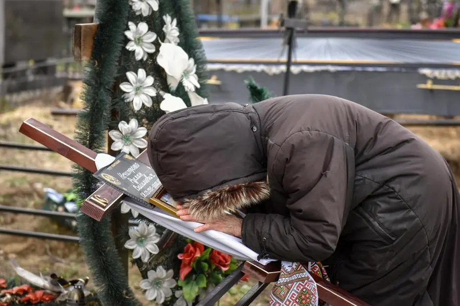 epaselect epa09895659 Alla, mother of the victim, who was killed by Russian soldiers in Bucha on March 17, mourns while holding a cross with his portrait on it, at the municipal cemetery in the recaptured city of Bucha of Kyiv (Kiev) area, Ukraine, 18 April 2022. Ukrainian authorities say that over 700 bodies were discovered following the Russian army’s retreat from towns surrounding Kyiv, prompting international calls for a probe into possible war crimes committed by Russia. EPA/OLEG PETRASYUK