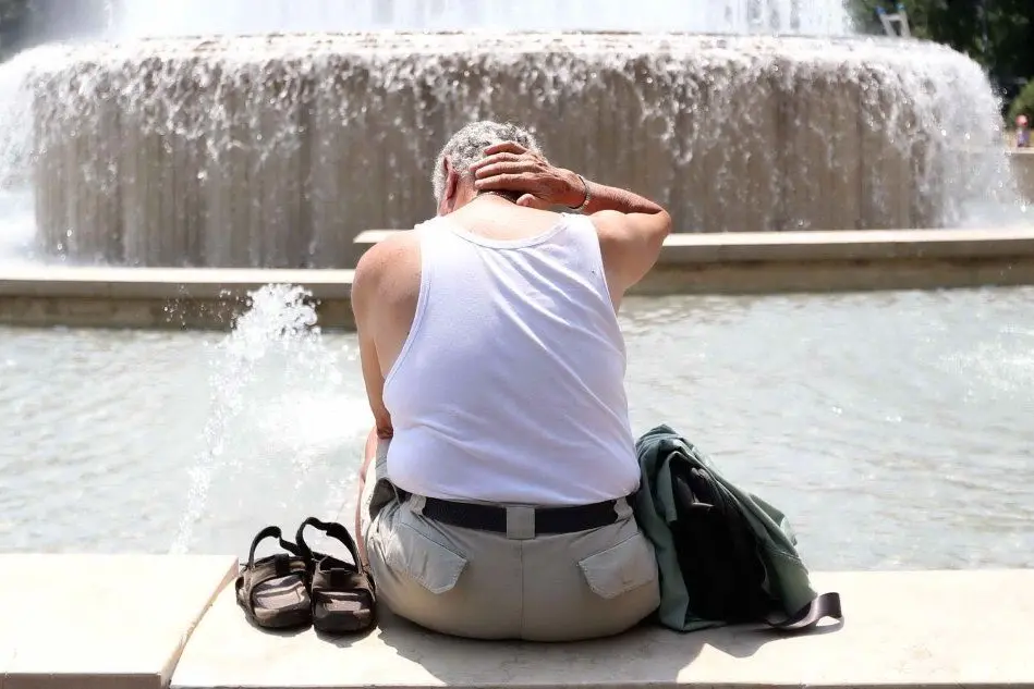 Un anziano cerca conforto sul bordo di una fontana