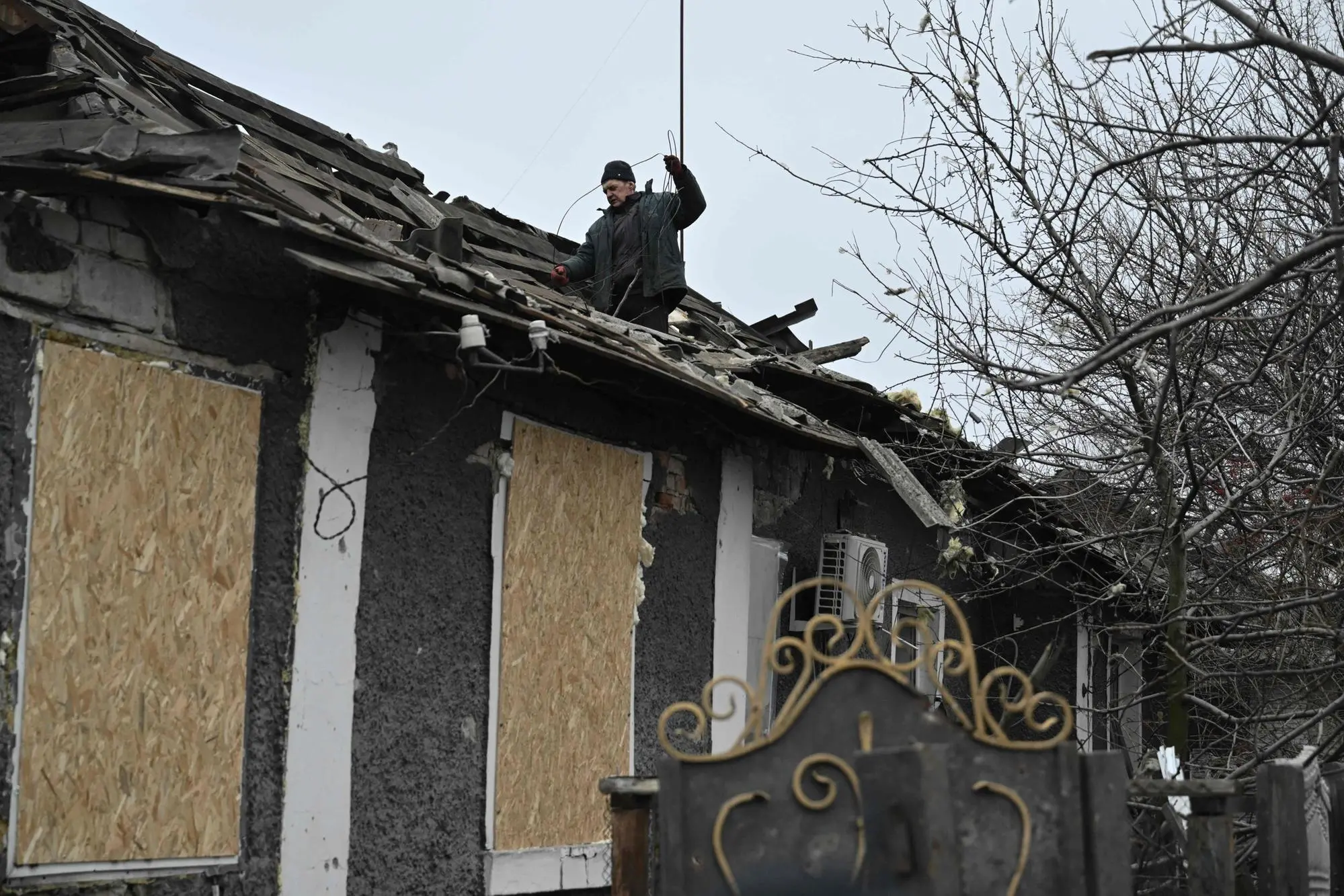 A man clears debris on a roof of a house damaged following a Russian airstrike in the town of Bilytske, near Pokrovsk in the Donetsk region on January 16, 2025, amid the Russian invasion of Ukraine. Russia's army is around six kilometres (four miles) from the centre of Pokrovsk, a formerly thriving mining hub on top of Ukraine's largest coal reserves. The capture of the city and surrounding mines, some of which are even closer to Russian positions, would be a painful blow to Ukraine's army, local communities and the national economy, compounding months of setbacks on the front. (Photo by Genya SAVILOV / AFP)