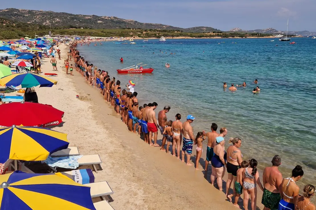 La catena umana in spiaggia a Cannigione