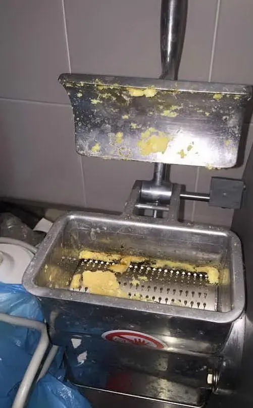 La macchina per grattugiare il formaggio vicino ai sacchi della spazzatura