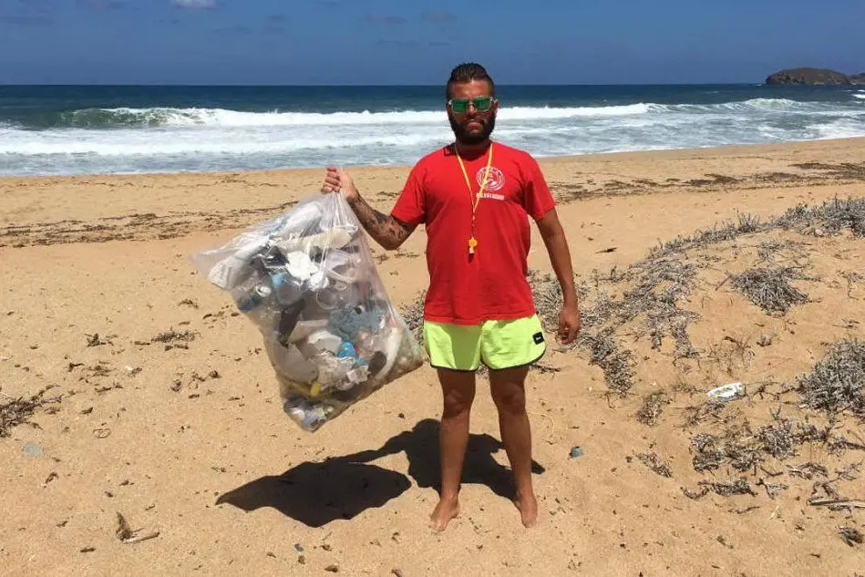 Cristian Pani con una busta di spazzatura raccolta alla spiaggia di Pistis