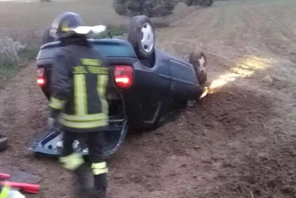 L'auto ribaltata e l'intervento dei vigili del fuoco (foto Gianluigi Deidda)