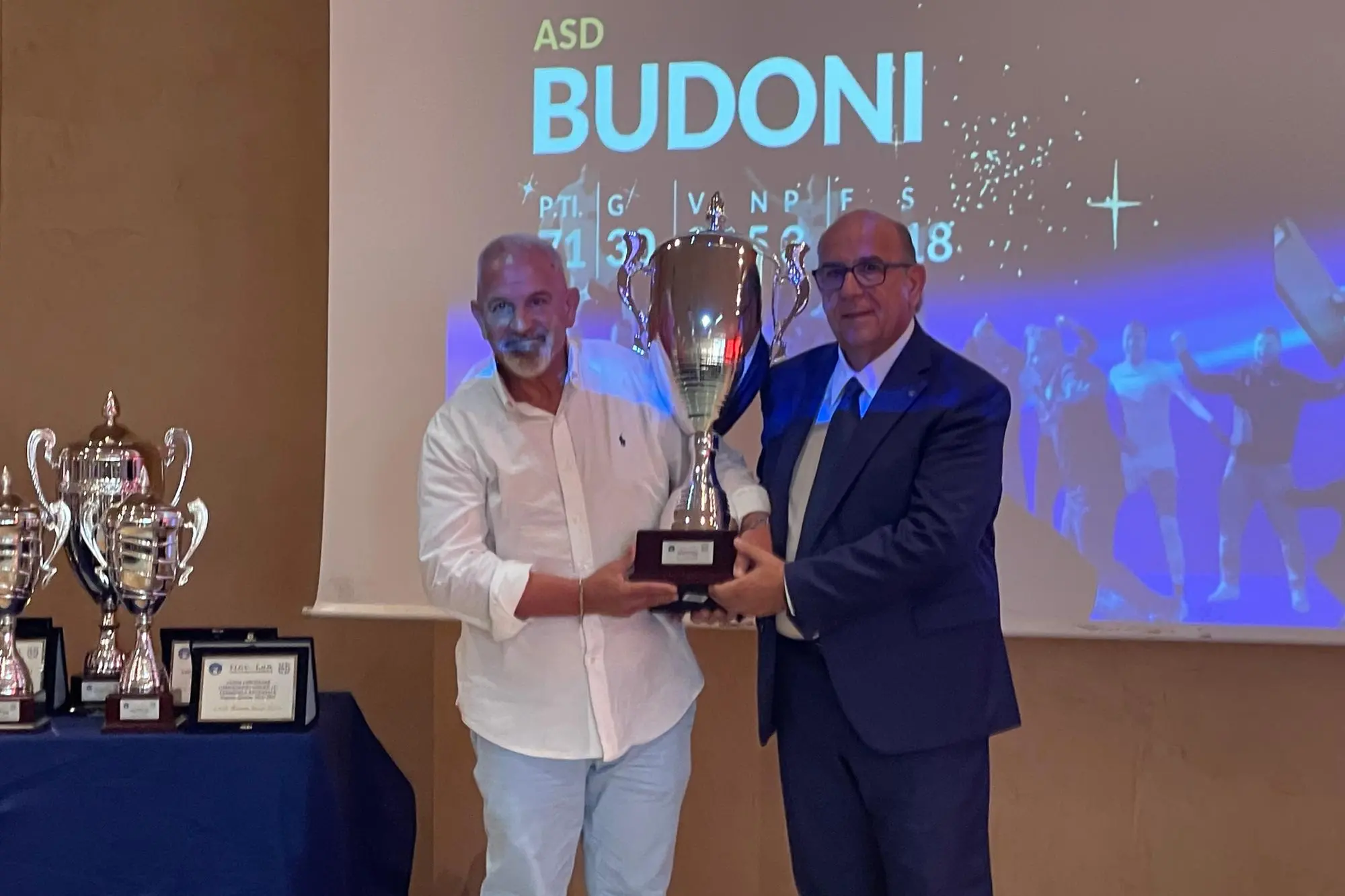 Filippo Fois, presidente del Budoni (a sinistra), riceve da Gianni Cadoni il premio per la vittoria dell'Eccellenza (foto Spignesi)