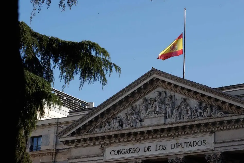 Bandiera spagnola a mezz'asta per le vittime del Covid (foto Ansa/Epa)