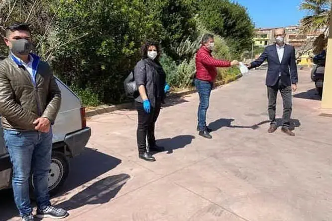 L'ex sindaco di Castelsardo Franco Cuccureddu (a destra) ieri mattina mentre consegna le mascherine (foto Facebook)