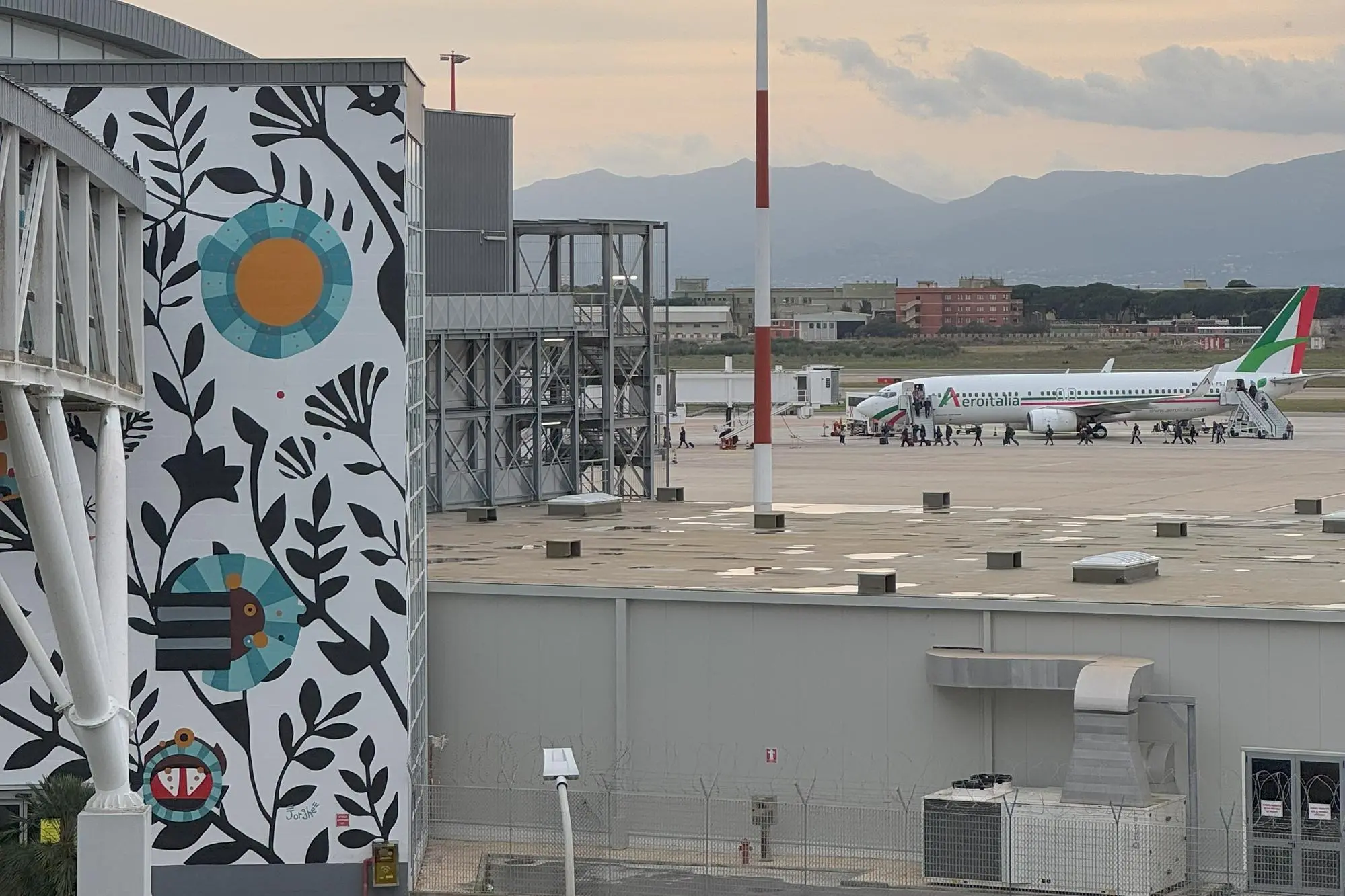 A sinistra, il murale di Giorgio Casu all'aeroporto di Cagliari