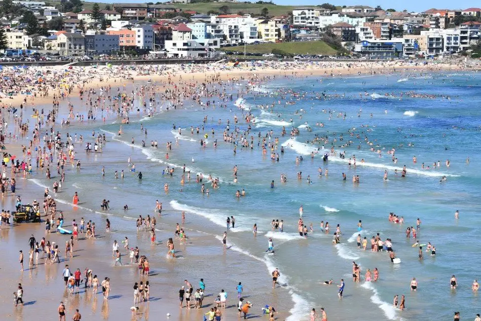 La spiaggia di Sidney piena di turisti nel giorno di Natale (Ansa)