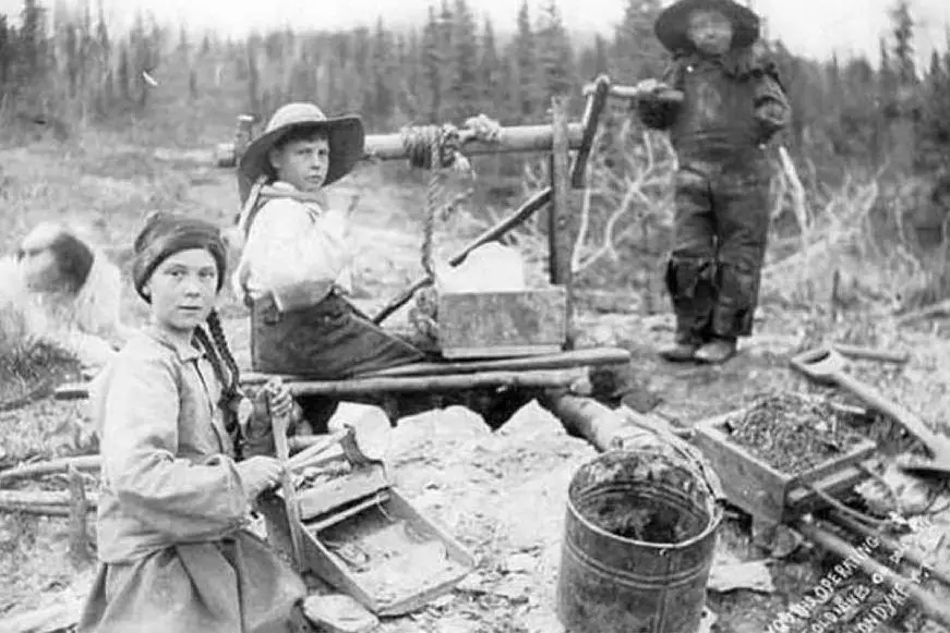 Lo scatto del 1898 (&quot;Three children operating rocker at a gold mine on Dominion Creek, Yukon Territory&quot;, University of Washington Libraries)