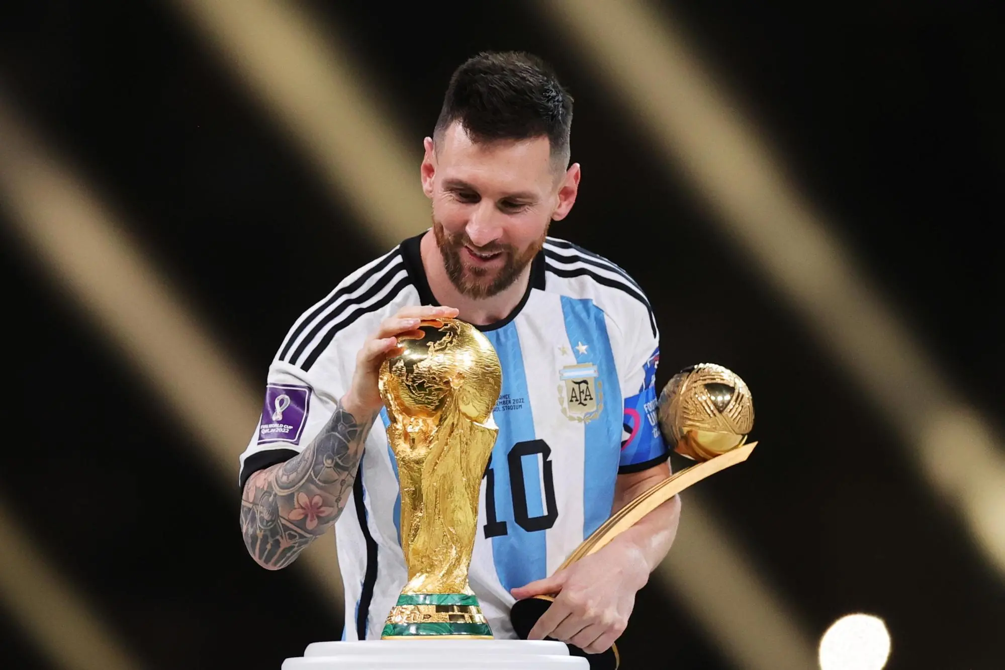 Lionel Messi of Argentina touches the World Cup trophy as he passes it after winning the golden ball award during the awards ceremony after the FIFA World Cup 2022 Final between Argentina and France at Lusail stadium, Lusail, Qatar, 18 December 2022. ANSA/Friedemann Vogel