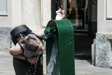 Una ragazza si disseta bevendo l'acqua fresca delle tipiche fontane dette Turet in piazza San Carlo, Torino, 18 giugno 2021. ANSA/TINO ROMANO