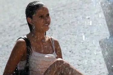 Una turista cerca un po' di fresco vicino a una fontana