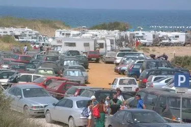 Camper e roulotte parcheggiati a ridosso della spiaggia di Piscinas