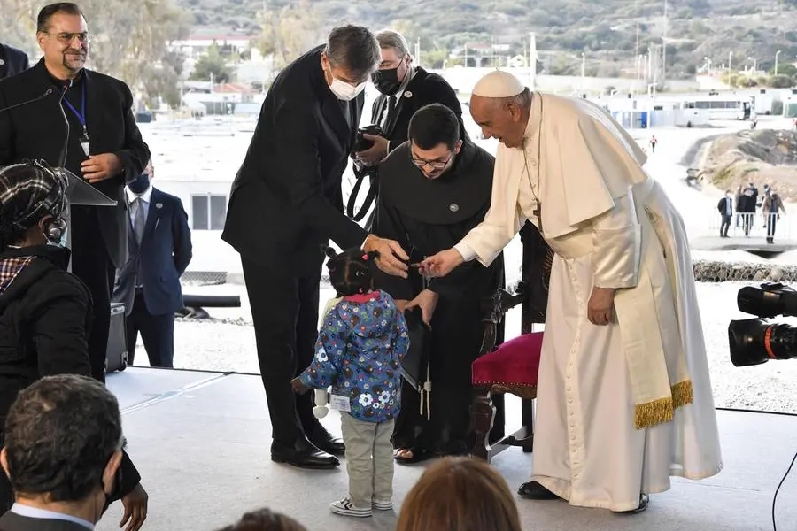 Il Papa con una piccola migrante (Ansa)