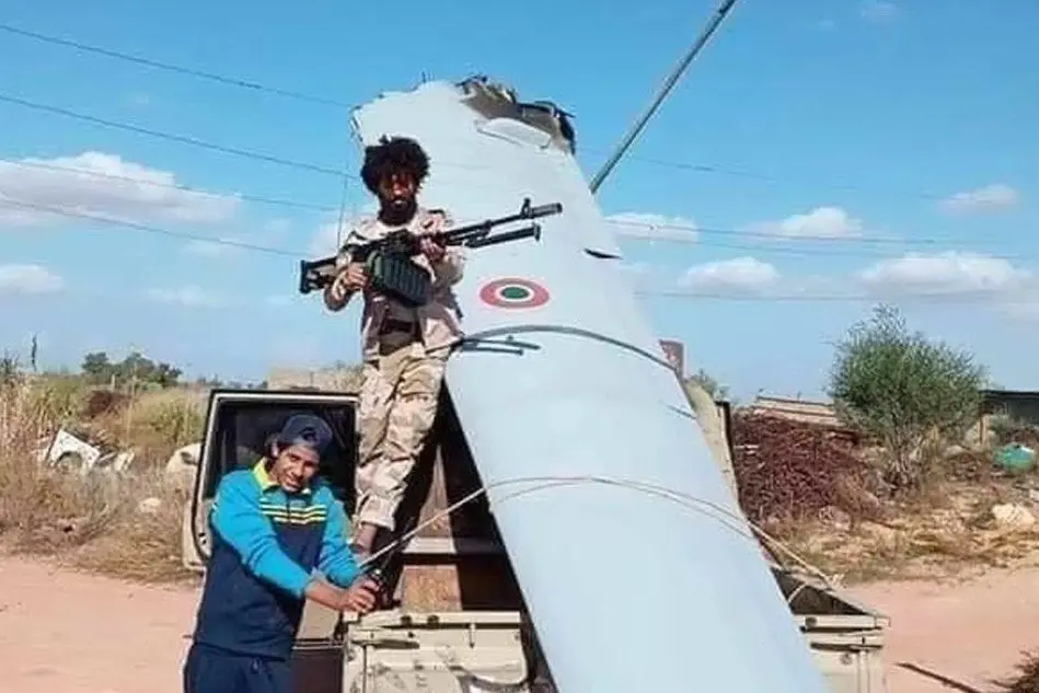 Miliziani in posa con un rottame del drone, in una foto circolata sul web (Ansa)