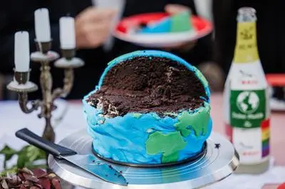 Una torta a forma di Terra come simbolo del consumo eccessivo delle risorse naturali nella protesta degli attivisti per l'ambiente (Ansa)