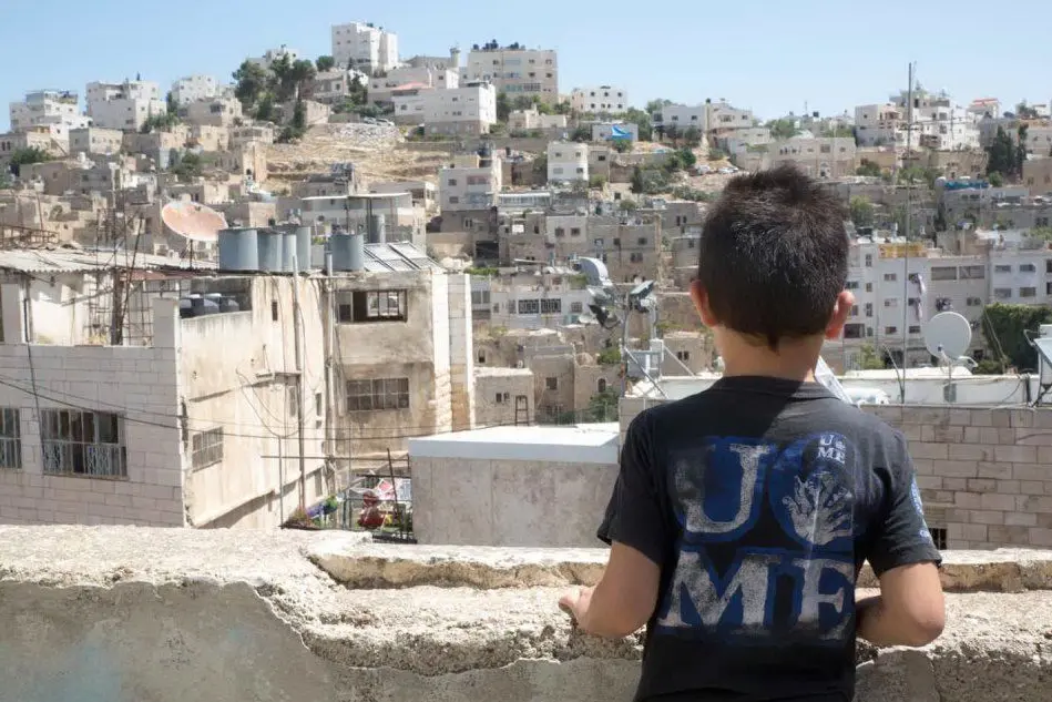 Un bambino palestinese guarda la città di Hebron (Ansa)
