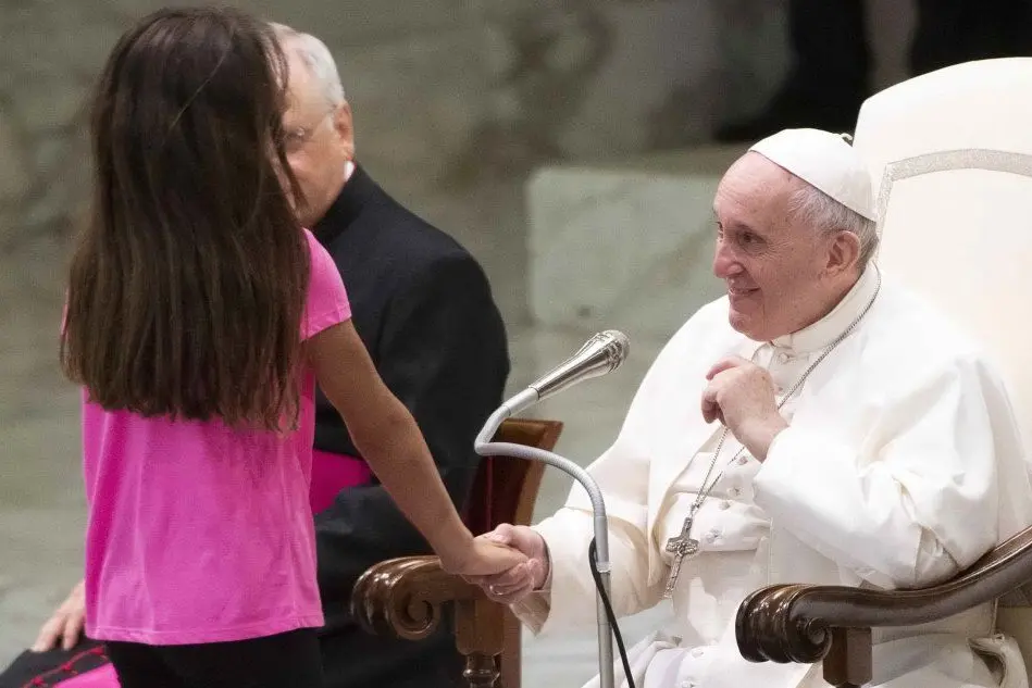 Papa Francesco prende la mano della bambina (Ansa)