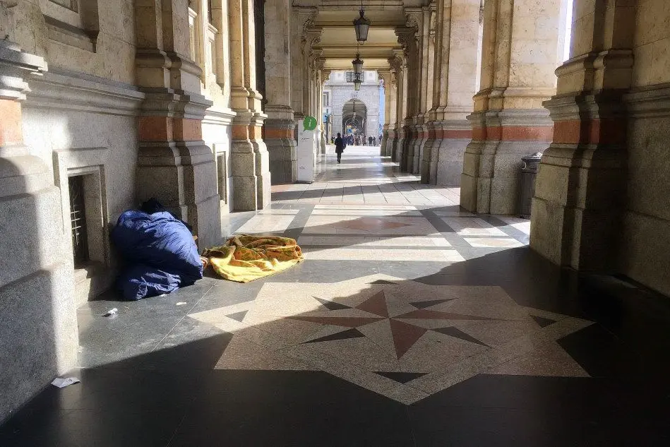 Un senzatetto dorme nei portici del Comune
