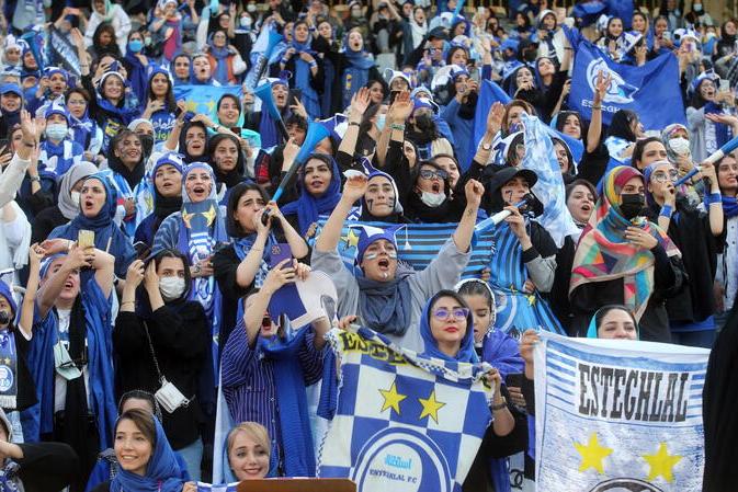 epa10138484 Iranian women soccer fans of Esteghlal-Tehran club cheer during the Iran Premier local soccer league match between Esteghlal and Mes-e Kerman at the Azadi stadium in Tehran, Iran, 25 August 2022. Iranian authorities for the first time allowed around 500 women soccer fans to attend at Iran Premier league. EPA/HOSSEIN ZOHREHVAND