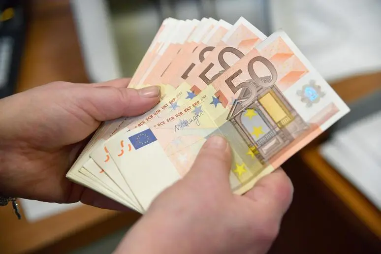 Alcune banconote da 50 Euro in mano a un cassiere di una banca
