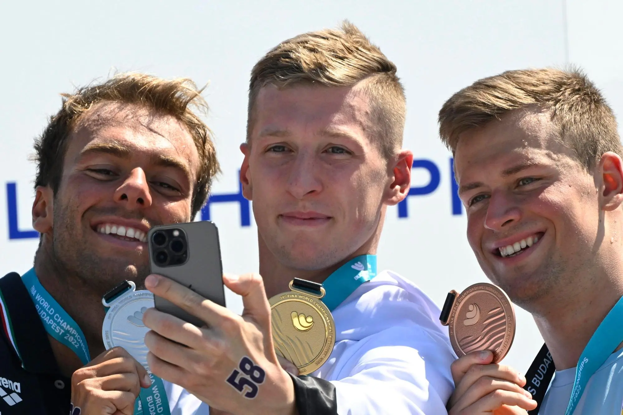 epa10036180 (L-R) Silver medalist Gregorio Paltrinieri of Italy, gold medalist Florian Wellbrock of Germany and bronze medalist Mykhailo Romanchuk of Ukraine pose for photographs during the award ceremony for the men's 5km open water swimming of the 19th FINA World Championships at Lupa lake near Budapest, Hungary, 27 June 2022. EPA/Zsolt Szigetvary HUNGARY OUT