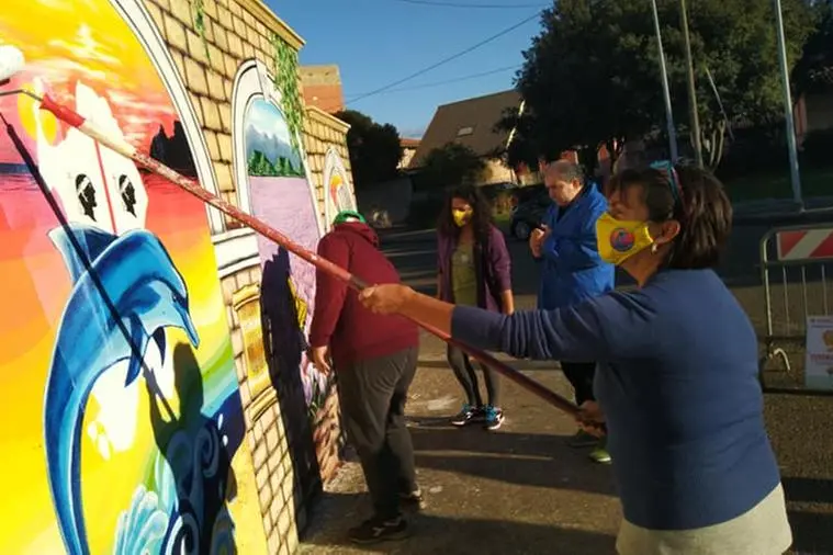 I ragazzi e i volontari dell'associazione Delfino al lavoro per la realizzazione del murale (foto Pittau)