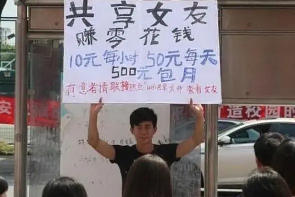 Il ragazzo cinese sorregge il cartello in cui &quot;offre&quot; la sua fidanzata