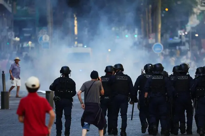 Police officers walk as they try to disperse protesters with tear gas during a demonstration against police in Marseille, southern France on July 1, 2023, after a fourth consecutive night of rioting in France over the killing of a teenager by police.. French police arrested 1311 people nationwide during a fourth consecutive night of rioting over the killing of a teenager by police, the interior ministry said on July 1, 2023. France had deployed 45,000 officers overnight backed by light armoured vehicles and crack police units to quell the violence over the death of 17-year-old Nahel, killed during a traffic stop in a Paris suburb on July 27, 2023. (Photo by CLEMENT MAHOUDEAU / AFP)