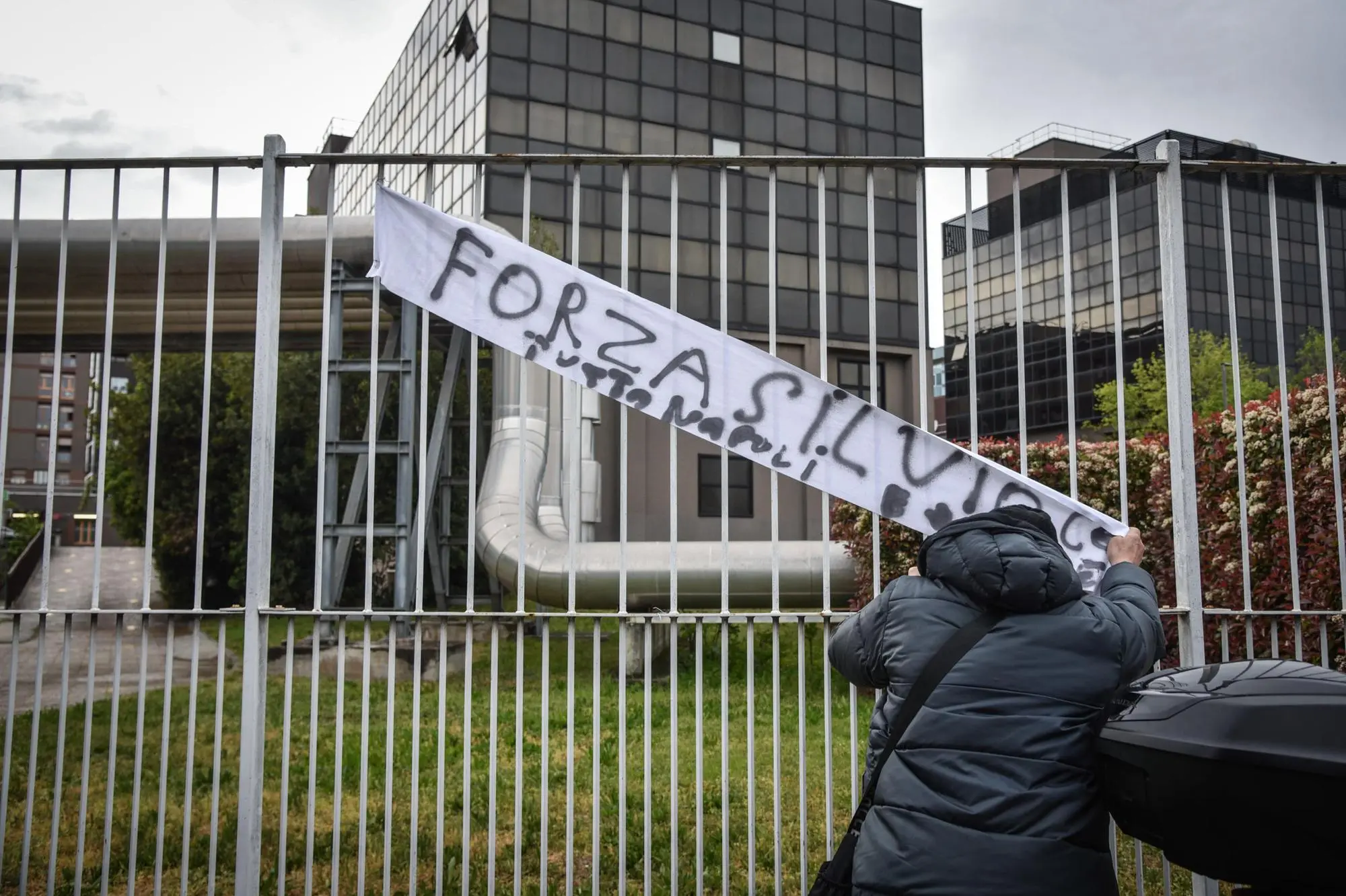 Il signor Antonio mette uno striscione per Silvio Berlusconi davanti all’ospedale San Raffaele (Ansa)