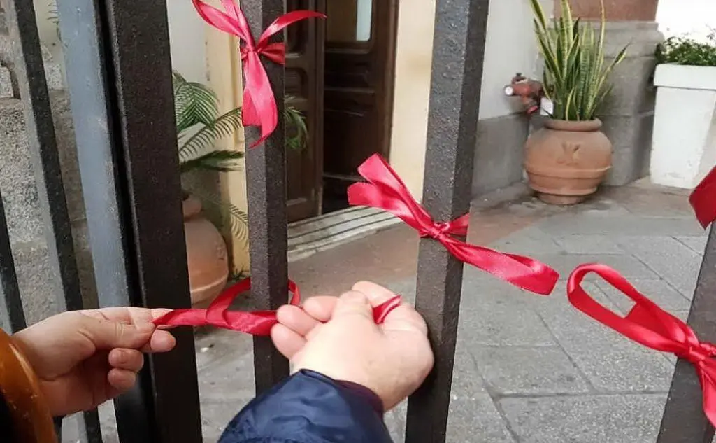 I nastrini rossi di solidarietà all'ingresso di Palazzo Civico in via Roma a Cagliari (foto Comune di Cagliari)