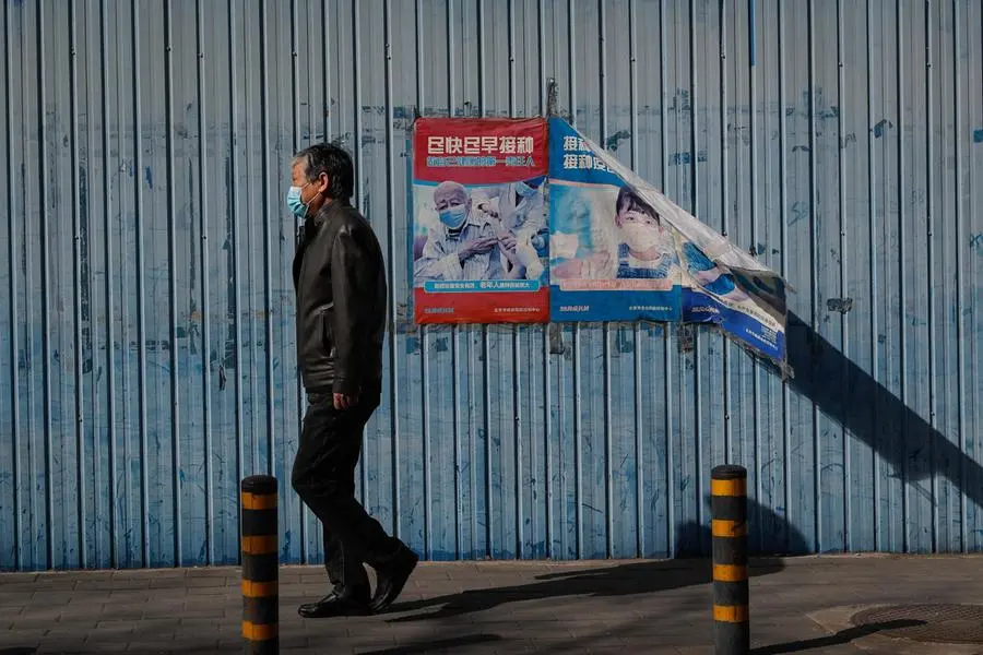epa09840225 A man walks past a Covid-19 vaccination poster in Beijing, China, 21 March 2022. According to a report from the National Health Commission, the Chinese mainland recorded 1,947 locally transmitted COVID-19 cases with a total of 80 imported COVID-19 cases, six of which are all imported, came from Shanghai. EPA/MARK R. CRISTINO