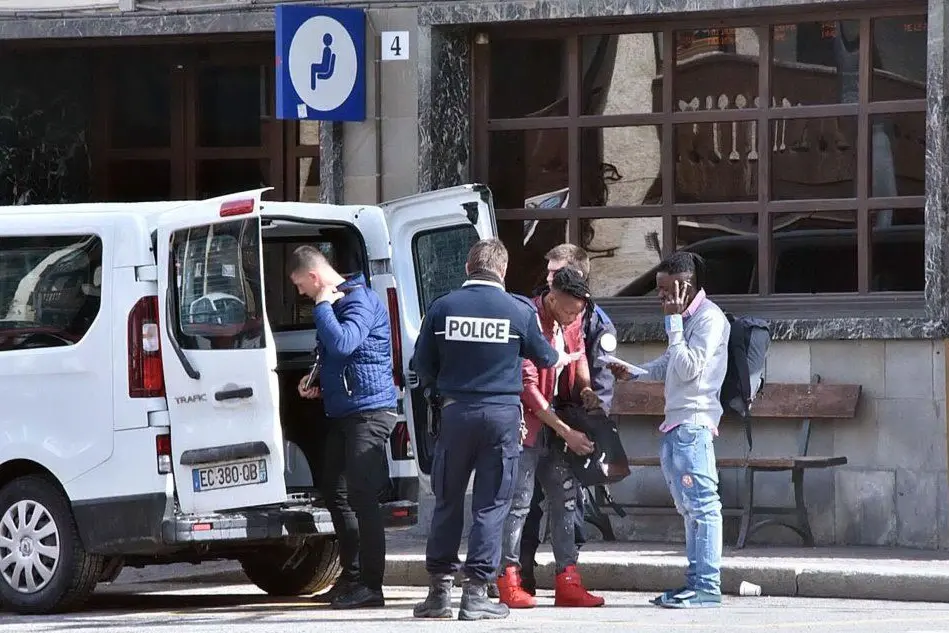Agenti della polizia francese e migranti al confine con l'Italia (Ansa)